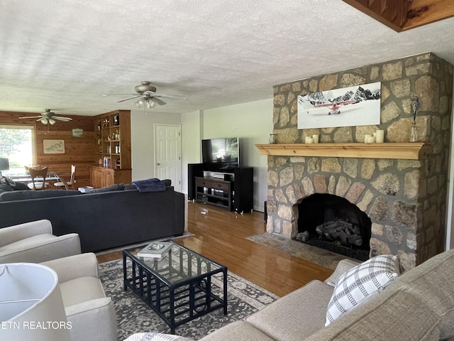 3576 E Atherton Ln, Baneberry, TN 37890 - living area with wood finished floors, ceiling fan, a stone fireplace, wood walls, and a textured ceiling