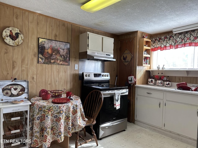 kitchen with a textured ceiling, light countertops, wood walls, under cabinet range hood, and stainless steel electric stove