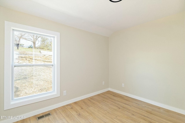 spare room with light wood-style flooring, baseboards, lofted ceiling, and visible vents