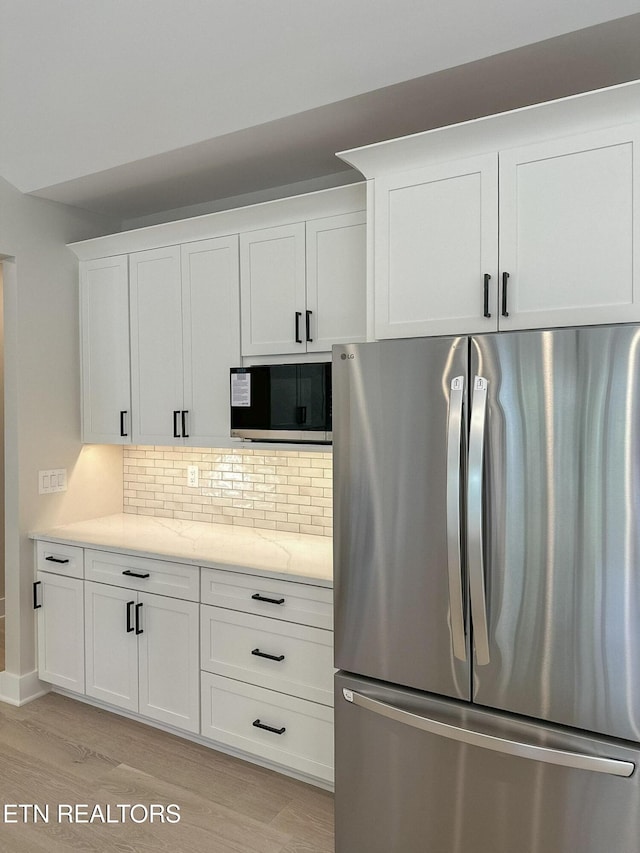409 Goweli Trl, Vonore, TN 37885 - kitchen with appliances with stainless steel finishes, light wood finished floors, white cabinetry, backsplash, and light stone counters