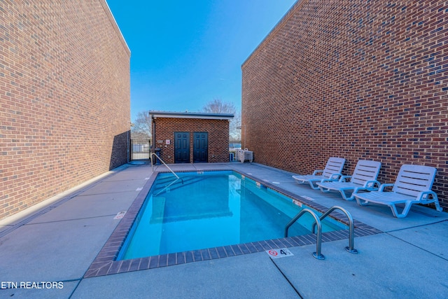 community pool featuring a patio, fence, and an outdoor structure