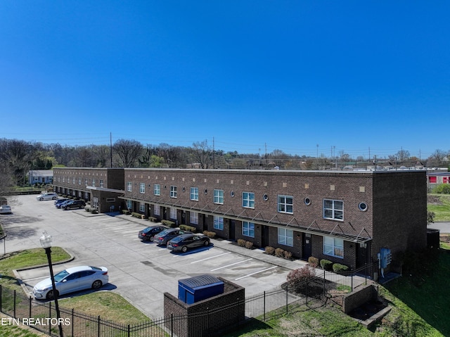 view of building exterior featuring fence, central AC unit, and uncovered parking