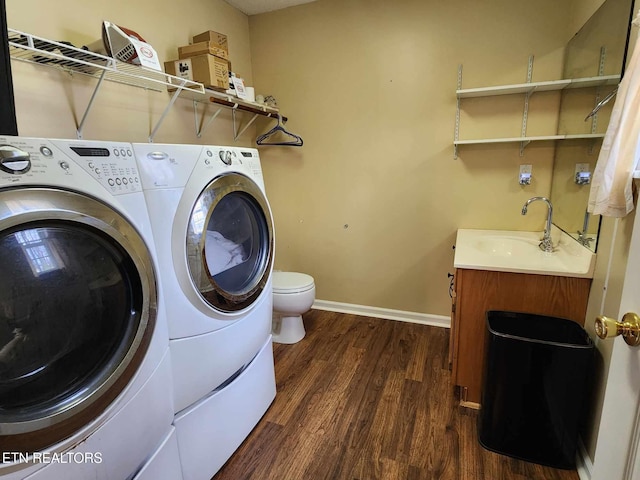 laundry room with baseboards, laundry area, dark wood-type flooring, a sink, and separate washer and dryer