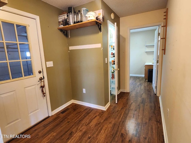 interior space featuring baseboards, dark wood-style flooring, a textured ceiling, and laundry area