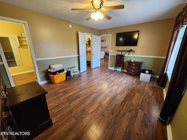 interior space with baseboards, wood finished floors, ceiling fan, and a textured ceiling