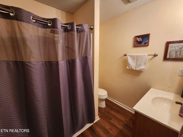bathroom featuring toilet, vanity, wood finished floors, a textured ceiling, and baseboards