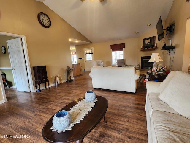 living room with high vaulted ceiling, baseboards, wood finished floors, a ceiling fan, and a glass covered fireplace