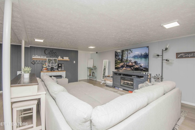 living area featuring baseboards, a textured ceiling, and wood finished floors