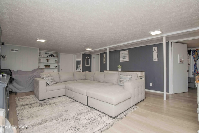 living room with wood finished floors, a textured ceiling, and visible vents