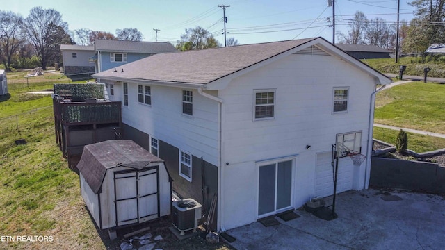 back of house with an outbuilding, roof with shingles, fence, central AC, and a storage shed