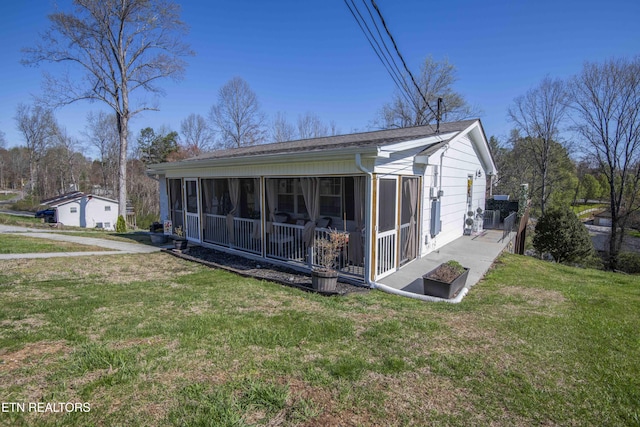 rear view of house featuring a lawn and a sunroom