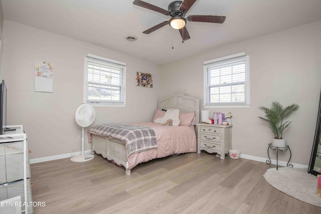 bedroom with baseboards, visible vents, multiple windows, and light wood finished floors