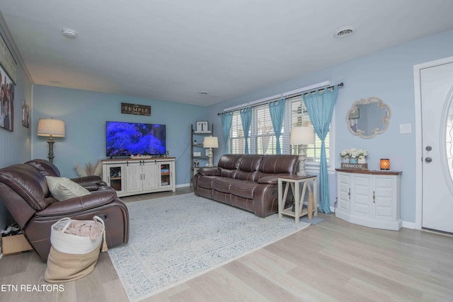 living room with baseboards, visible vents, and wood finished floors