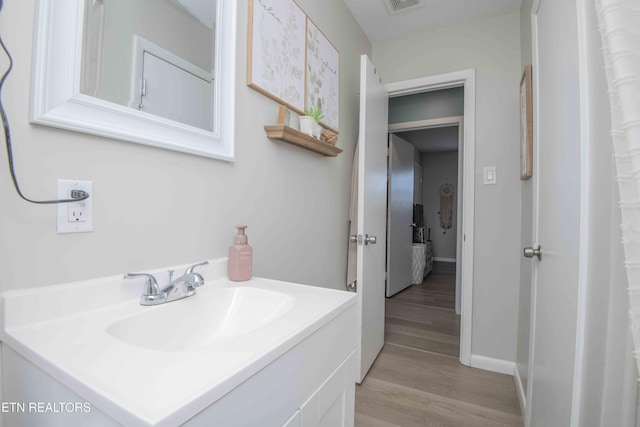 bathroom featuring vanity, baseboards, visible vents, and wood finished floors