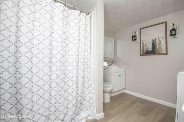 full bathroom with vanity, toilet, baseboards, curtained shower, and wood finished floors