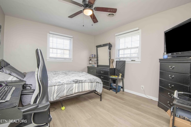 bedroom featuring baseboards, light wood-style flooring, and multiple windows