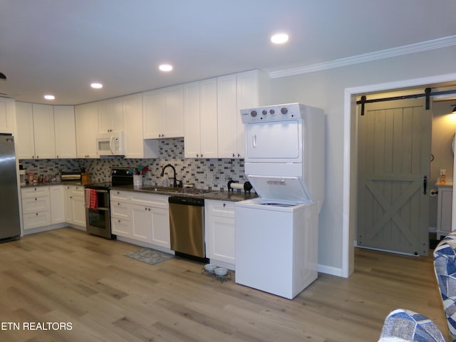 kitchen with tasteful backsplash, a barn door, stacked washer / dryer, appliances with stainless steel finishes, and crown molding