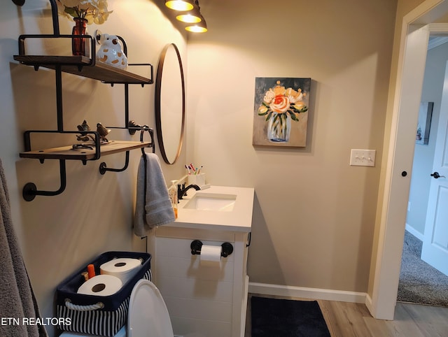 bathroom with baseboards, wood finished floors, and vanity
