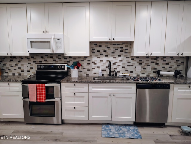 kitchen with white cabinetry, stainless steel appliances, light wood-type flooring, and a sink
