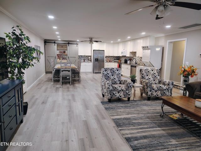 living area with visible vents, a barn door, ornamental molding, and a ceiling fan