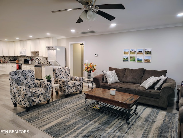 living area with crown molding, ceiling fan, visible vents, light wood-type flooring, and recessed lighting