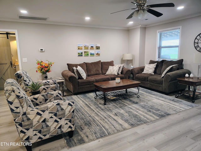 living room featuring ceiling fan, visible vents, light wood-type flooring, and a barn door