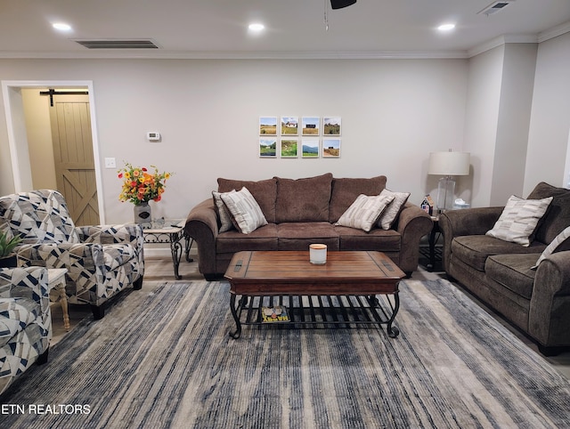 living room with crown molding, visible vents, a barn door, recessed lighting, and wood finished floors