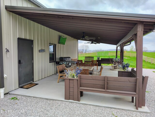 view of patio / terrace with an outdoor living space, fence, a carport, and a ceiling fan