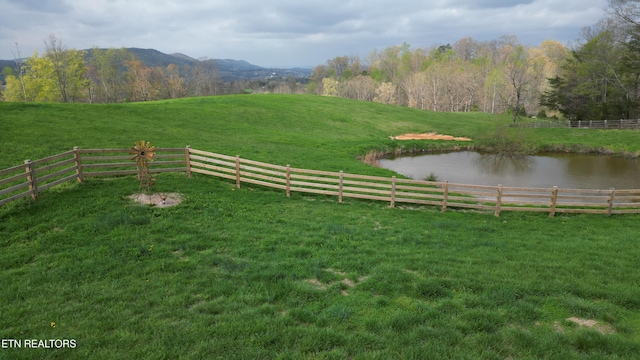view of yard with fence, a rural view, and a water and mountain view
