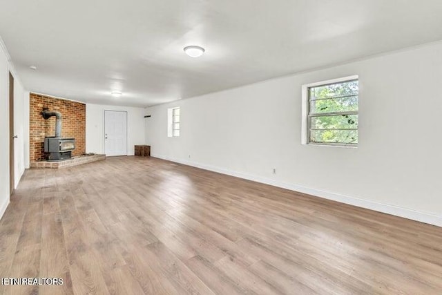 unfurnished living room featuring a wood stove, wood finished floors, and baseboards