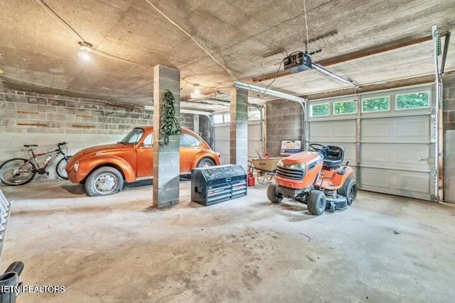 garage featuring a garage door opener and concrete block wall
