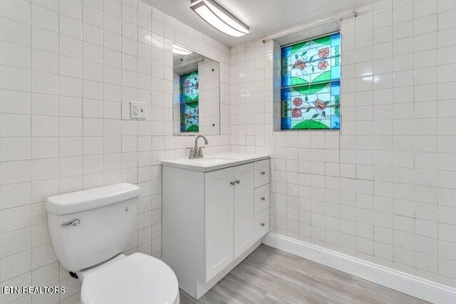 bathroom with vanity, tile walls, toilet, and wood finished floors
