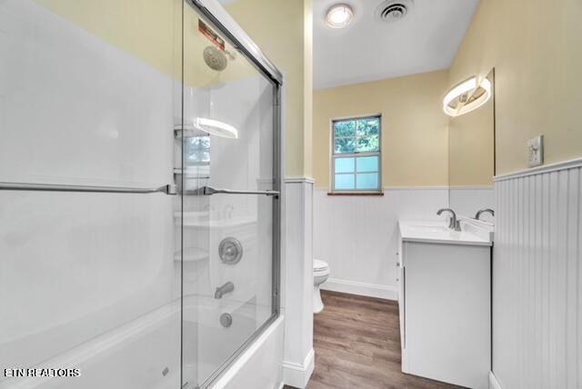 full bath with vanity, visible vents, a wainscoted wall, toilet, and wood finished floors