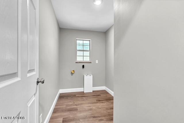 washroom with hookup for an electric dryer, baseboards, wood finished floors, and laundry area