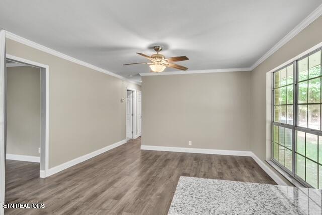spare room featuring ornamental molding, baseboards, a ceiling fan, and wood finished floors
