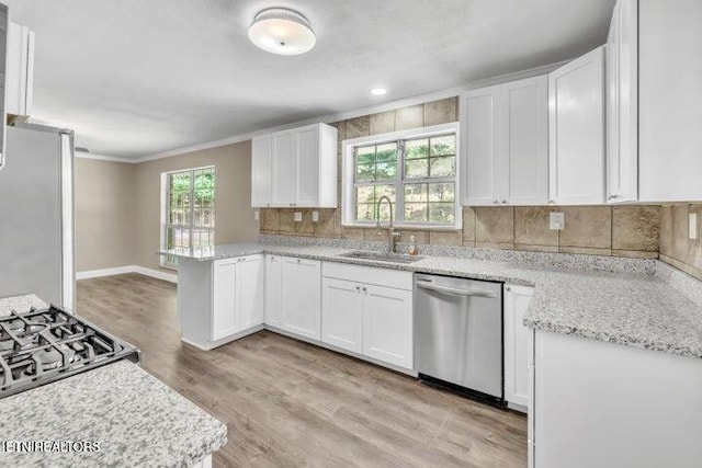 kitchen with appliances with stainless steel finishes, decorative backsplash, a sink, and white cabinets