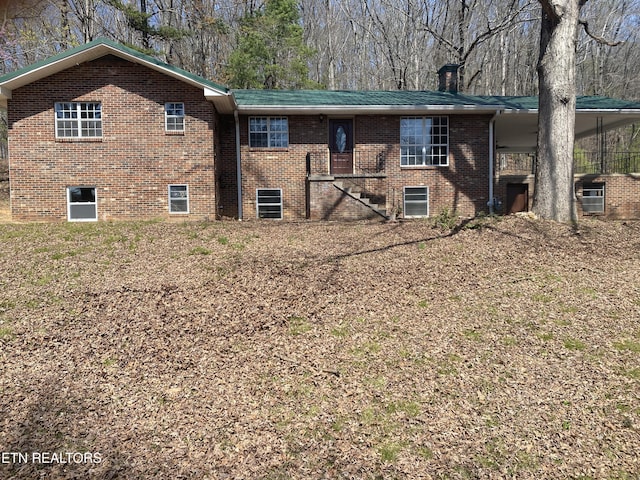 rear view of property featuring brick siding and a chimney