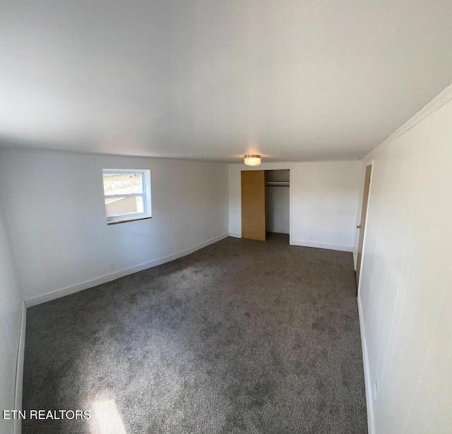 empty room featuring dark carpet and baseboards