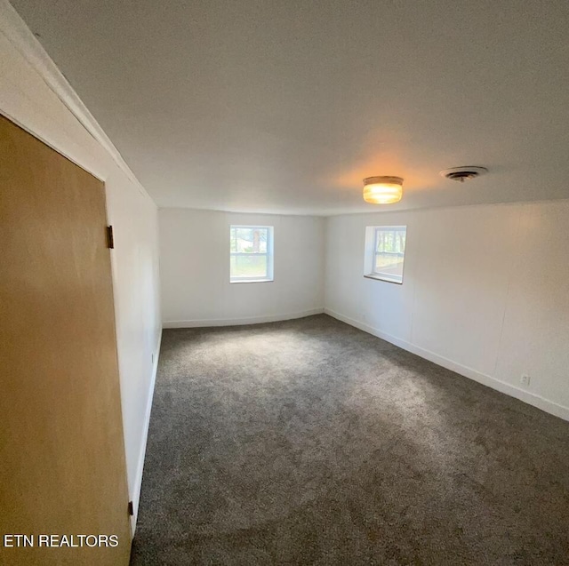 empty room with a wealth of natural light, carpet flooring, visible vents, and baseboards