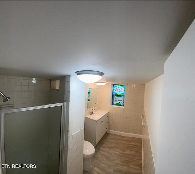 full bathroom featuring vanity, toilet, wood finished floors, tile walls, and a stall shower