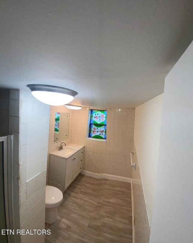 bathroom featuring vanity, tile walls, toilet, and wood finished floors