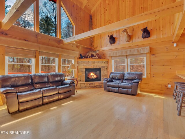 2164 Newt Huff Ln, Sevierville, TN 37862 - living room with wood finished floors, wood walls, a stone fireplace, beamed ceiling, and a towering ceiling
