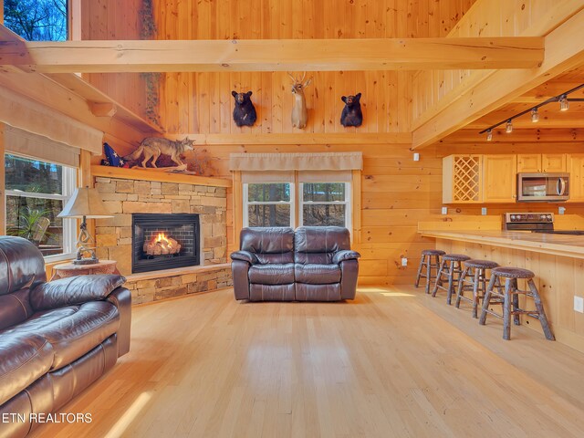 2164 Newt Huff Ln, Sevierville, TN 37862 - living room with wood walls, beamed ceiling, rail lighting, wood finished floors, and a stone fireplace