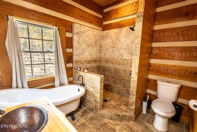 full bathroom with a freestanding bath, toilet, walk in shower, tile patterned flooring, and wooden walls