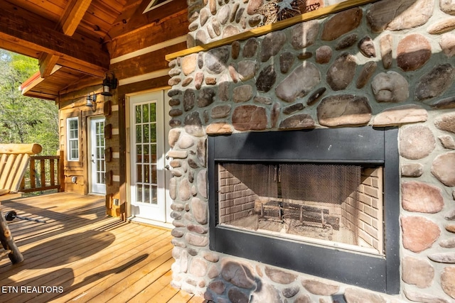 interior details with an outdoor stone fireplace and wood walls