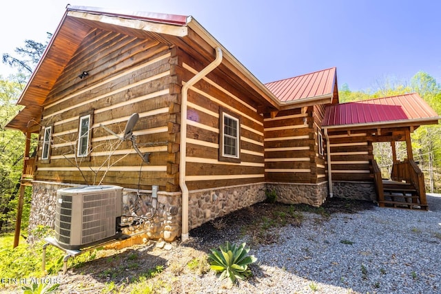 view of side of home featuring log siding, central air condition unit, and metal roof