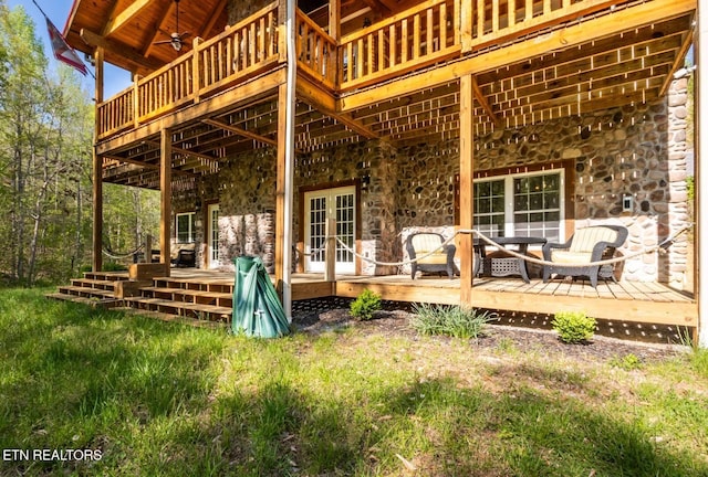 rear view of property with a wooden deck, stone siding, and french doors