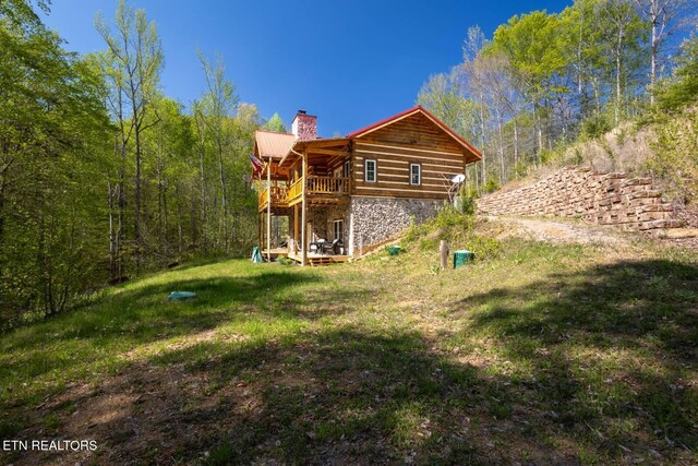 rear view of property featuring stone siding, a chimney, stairway, and a deck