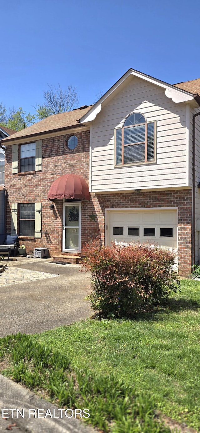 view of front of property with brick siding, a front yard, and a garage