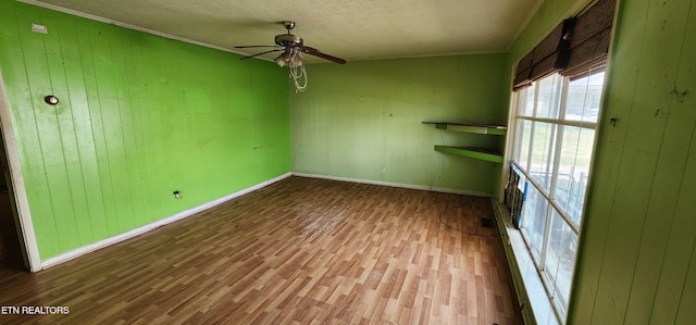 spare room featuring baseboards, a textured ceiling, wood finished floors, and a ceiling fan